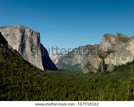 Yosemite Valley from Tunnel View on a sunny day. This is a famous point of view where we can see El Capitan and Bridalveil Fall rising from Yosemite Valley, with Half Dome in the background.