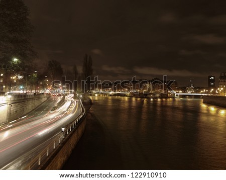Night traffic along the river Seine in Paris, capital of France, with car lights in motion blur.