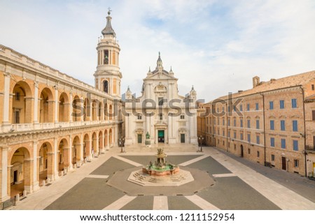Square of Loreto, Basilica della Santa Casa in sunny day, portico to the side, people in the square in Loreto, Ancona in Italy