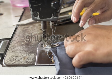 Woman hands sewn fabric repairs on sewing machine in Sewing Process.