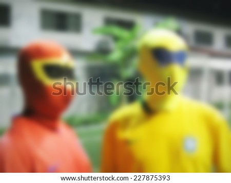defocused of two men with masks in red and yellow cloths.
