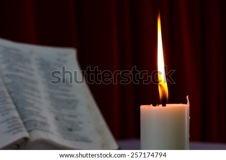 bible open on a table with candle in the dark. Perfect for religion, easter and christmas themes. candle fucused