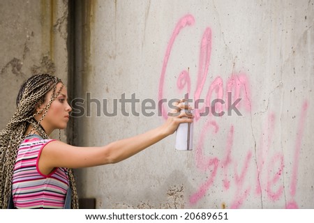 girl painting on the gray and dirty wall