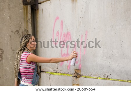 girl painting on the gray and dirty wall