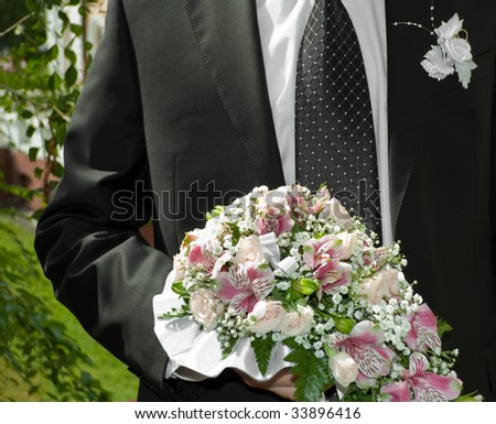 man in black coat with bridal bouquet