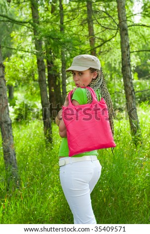 beauty girl in the cap with pink bag on the forest background