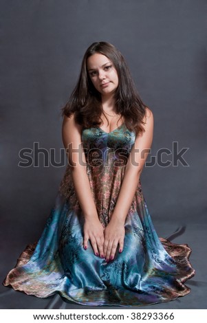 beauty and modest girl in versicolor dress on the gray background