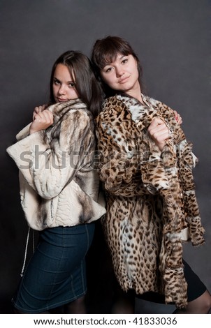 two sexy girls in fur coat on gray background