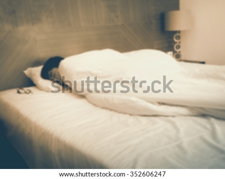 Blurry sleeping young man, closed eyes, black hair with blurred lights in corner. Vintage tone.