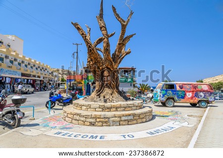 MATALA, CRETE, GREECE - AUGUST 20, 2013: Famous tree, hippie bus and paints on road in Matala center on Crete island