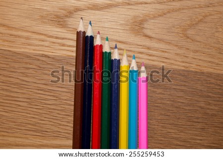Color pencils next to each other in stairs look on wooden table