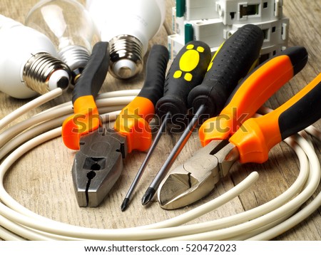 set of electrician tools, a coil of wire and equipment in background