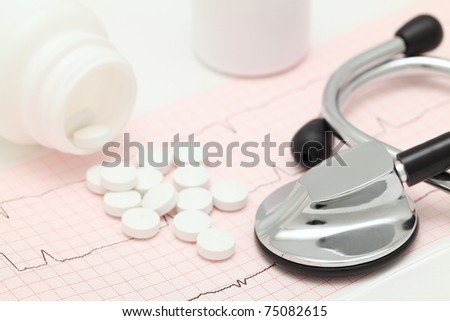 Medical still-life with cardiogram, stethoscope and spilled tablets