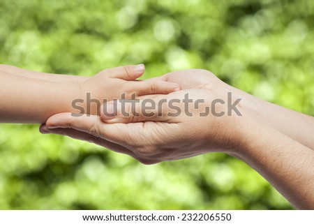 Father and son, holding hands on nature background.