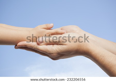 Father and son, holding hands on sky background.