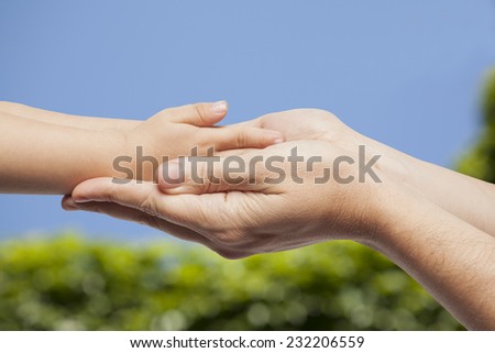 Father and son, holding hands on nature background.