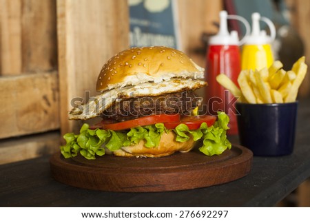 hamburger with vegetables and fries on wooden table