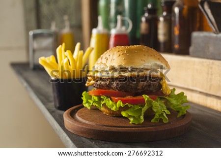 hamburger with vegetables and fries on wooden table