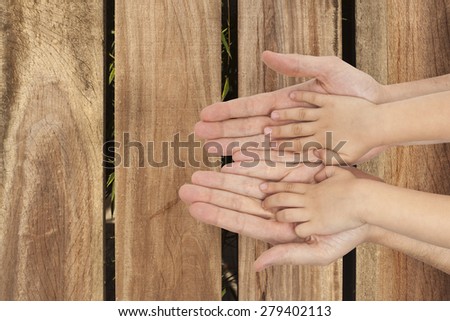 father and son holding hands on wooden wall background