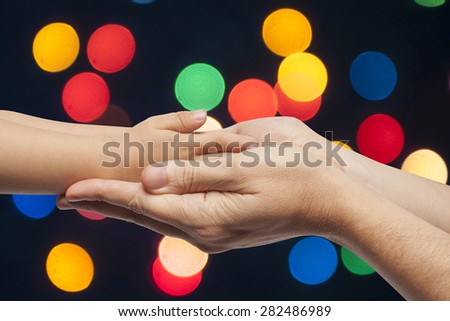 father and son holding hands on multicolored christmas lights background
