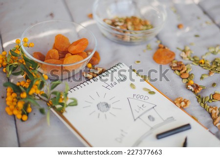composition of dried apricots,walnuts,pumpkin seeds and almond lying on the paper where diet and food written in the notebook.