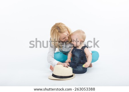happy and smiling baby boy with his mother sitting on the floor with  white hat and having fun