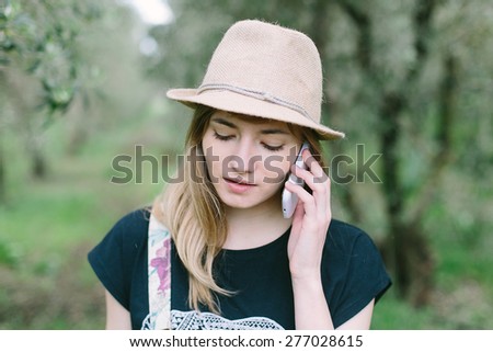 Pretty young girl calling on a mobile phone outdoors among trees