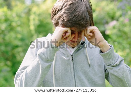 Young man having eye pain and rubbing his eyes