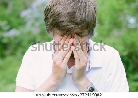 Young man having eye pain and rubbing his eyes