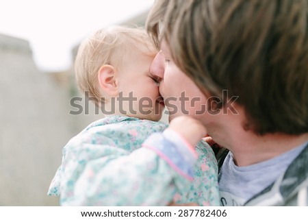 Father kisses little cute baby with a tear on her cheek