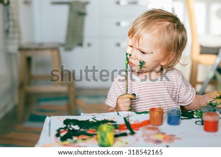 Happy cute toddler painting with gouache paints