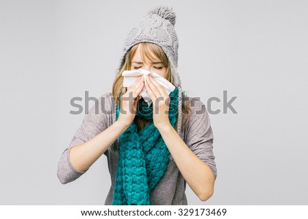 sick young woman blowing her nose isolated on light background