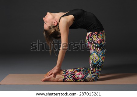 Woman doing yoga in studio on grey background.