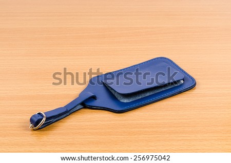 blue leather luggage tag on wooden background