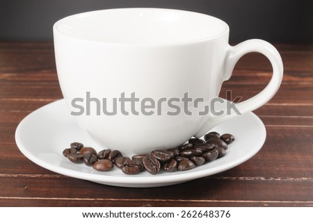 roasted coffee beans in coffee cup on wooden board with black  background