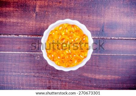 Fish oil in white bowl porcelain with wooden texture background