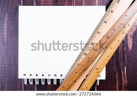 Wooden ruler and notebook on wooden board background