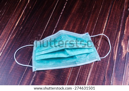Green disposable face mask on wooden background