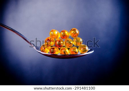 Fish oil on silver spoon with blue background
