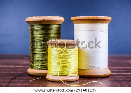 Vintage grunge three wooden threads spools on wooden board background