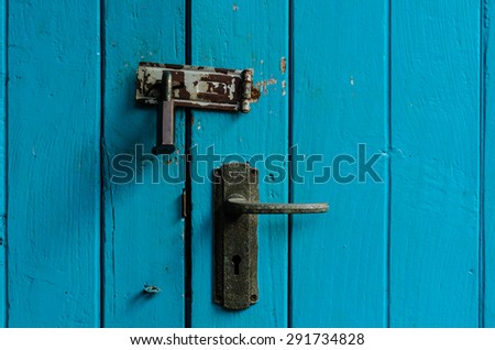 Old door handle with retro padlock on wooden plank texture background