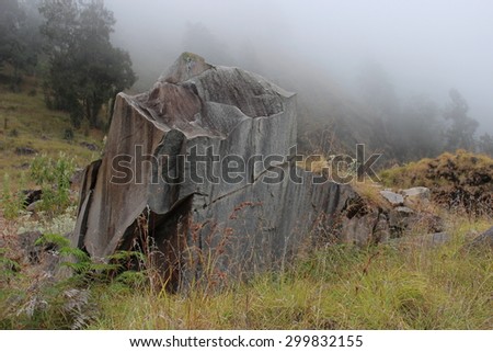 Igneous rock standing alone on a mountainside with mist.. Rinjani volcano, Lombok.