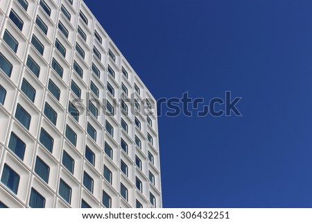 Sky scraper tower block, white against deep blue sky. Repetitive pattern of square windows. Perth, Australia.
