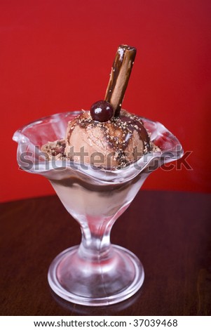 Chocolate ice-cream sundae with flake and a glazed cherry on top, served in a pretty glass.