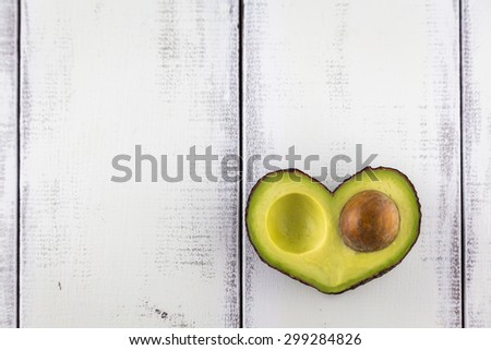 Avocado in the shape of a heart on a rustic white table
