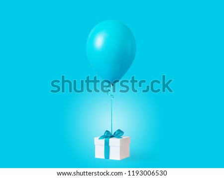White gift box with blue ribbon and balloon on blue background. Minimal concept, christmas, new year