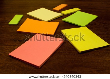 Close up of post it pads / notes lying on an office table. The notes are of different sizes and colors.