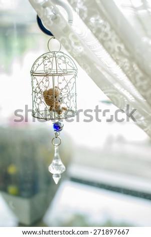 soft focus on bear doll in cage hanging on window shades