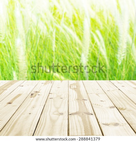Wood table top on blurry grass flowers backgrounds.