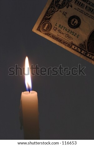 Money to burn.  A dollar bill being lowered into a candle flame.